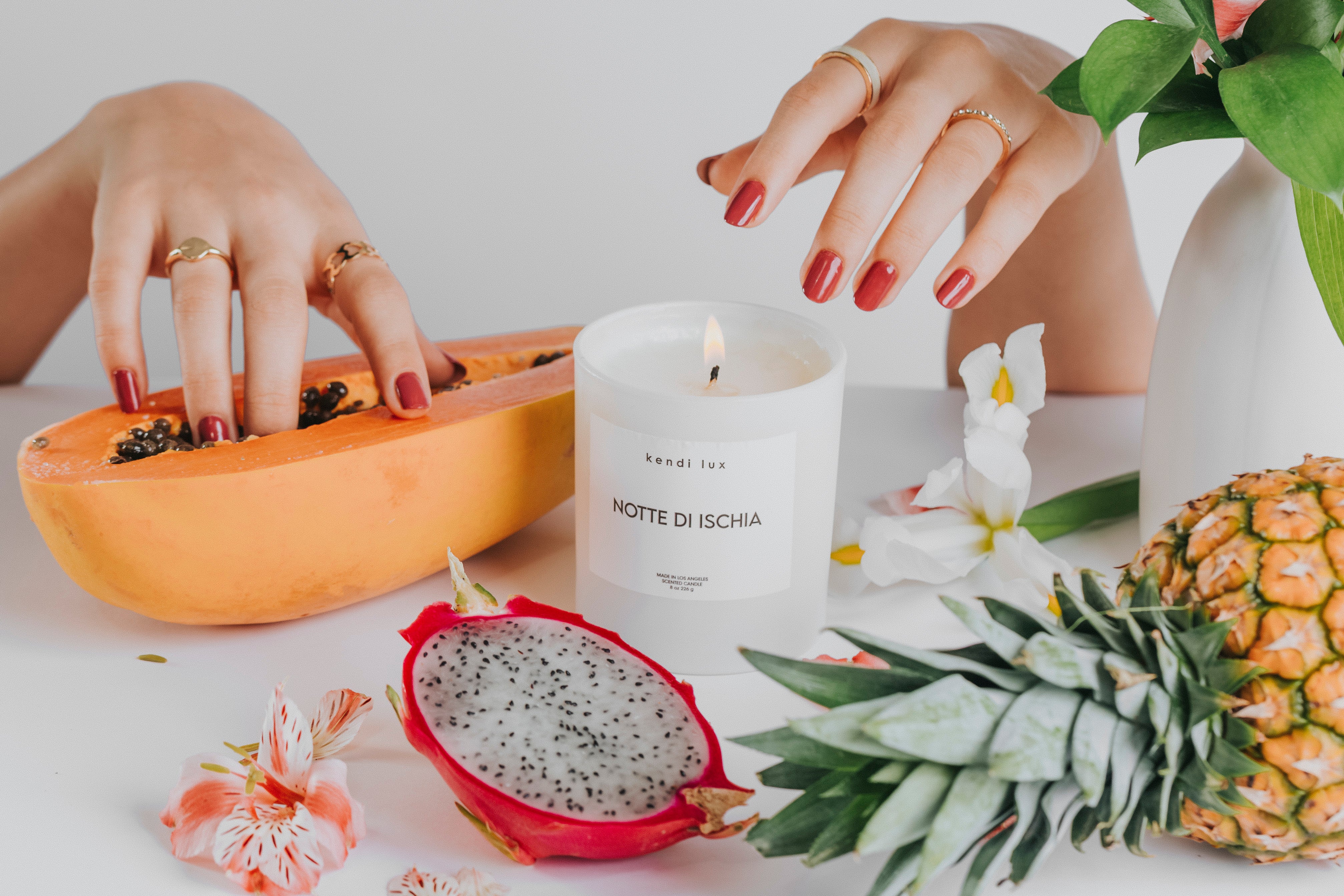 'Notte di Ischia' candle with 'kendi lux' branding on a table with fruit and flowers